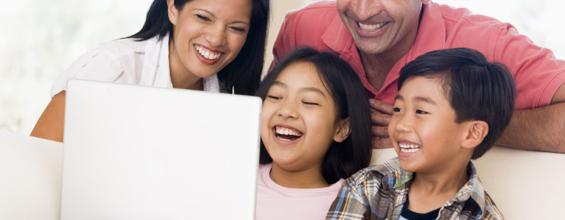 Family in living room with laptop smiling